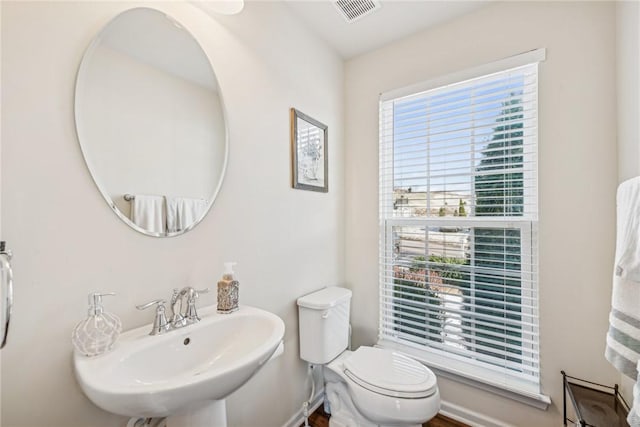 bathroom with toilet, a sink, and visible vents