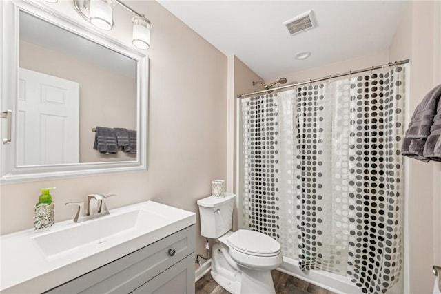 bathroom with visible vents, toilet, a shower stall, vanity, and wood finished floors