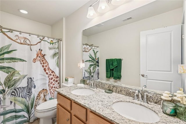 bathroom with a sink, visible vents, toilet, and double vanity