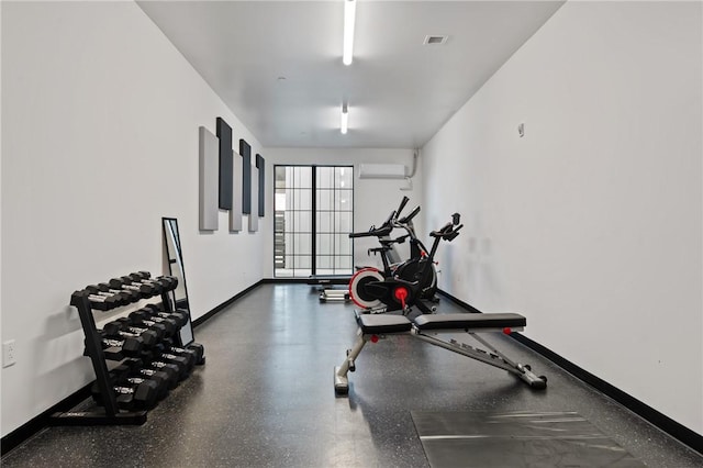 exercise room with a wall mounted air conditioner, visible vents, and baseboards