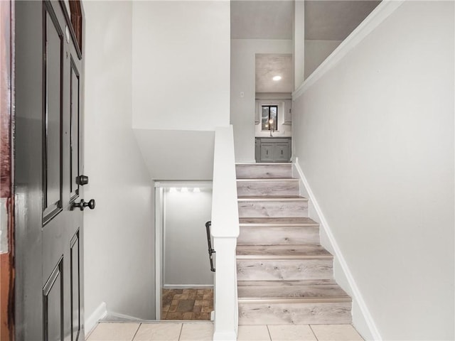 staircase featuring tile patterned floors and baseboards