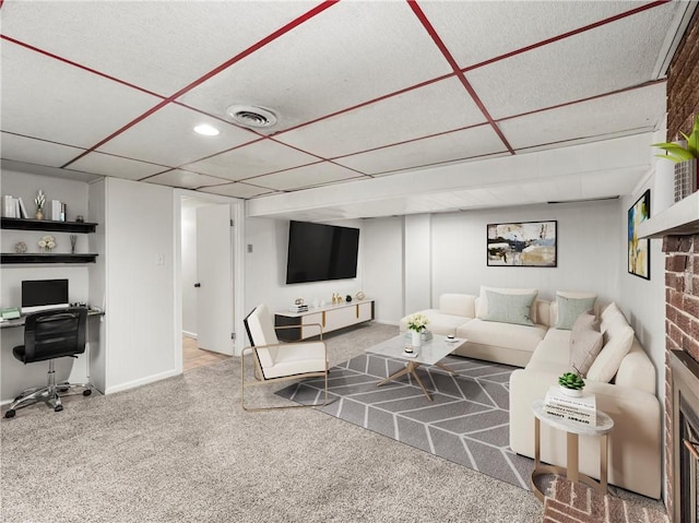 living room featuring carpet flooring, baseboards, a drop ceiling, and visible vents