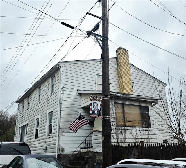 view of home's exterior with entry steps, fence, and a chimney