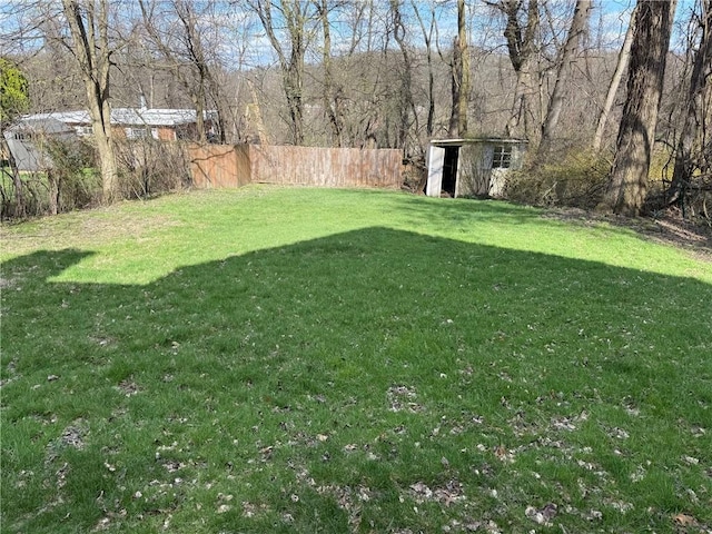 view of yard featuring a shed, an outdoor structure, and fence