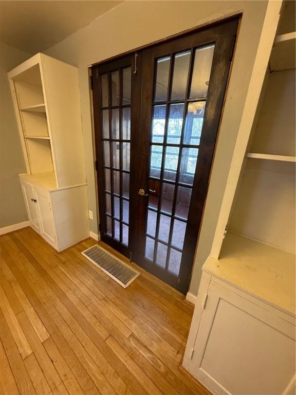 doorway featuring french doors, visible vents, wood-type flooring, and baseboards