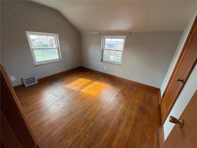 additional living space with visible vents, hardwood / wood-style flooring, baseboards, and lofted ceiling