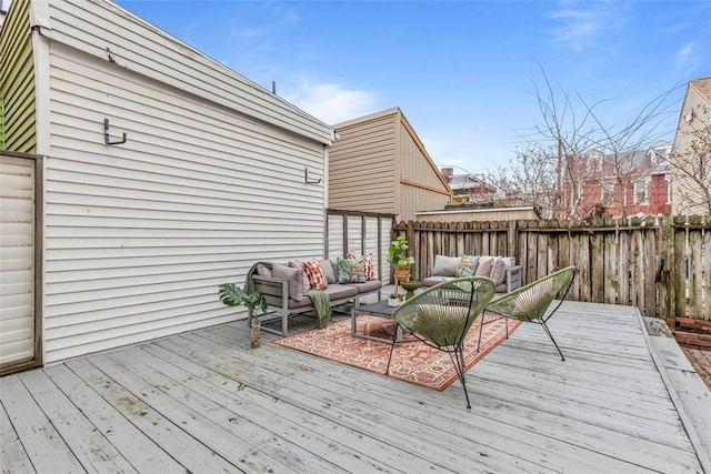 wooden terrace with an outdoor hangout area and fence