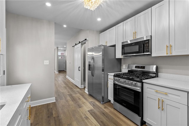 830 Adelaide St, Schenley Heights, PA 15219 - kitchen featuring baseboards, recessed lighting, dark wood-style floors, a barn door, and appliances with stainless steel finishes