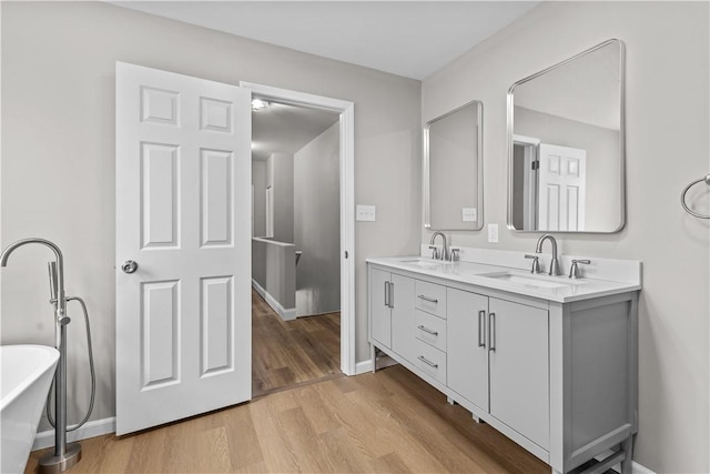 830 Adelaide St, Schenley Heights, PA 15219 - bathroom with wood finished floors, a sink, a freestanding bath, double vanity, and baseboards