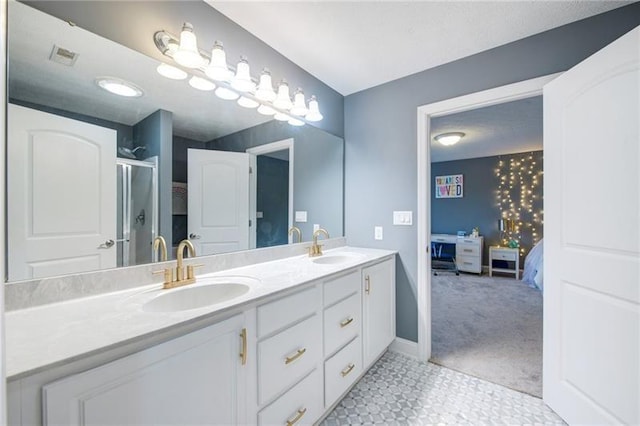 bathroom featuring a shower with shower door, double vanity, a sink, and baseboards