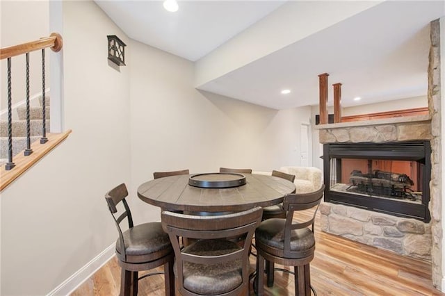 dining area featuring wood finished floors, baseboards, a stone fireplace, and recessed lighting