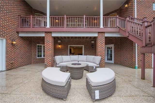 view of patio featuring an outdoor living space with a fire pit and a balcony