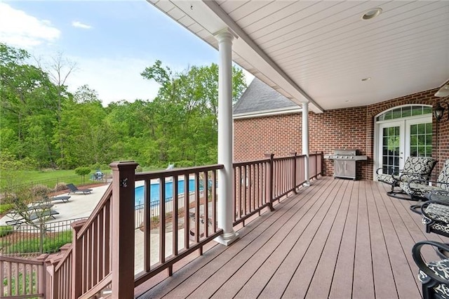 wooden terrace with a fenced in pool, french doors, and a grill