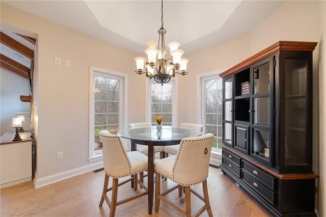 dining space with visible vents, baseboards, a notable chandelier, light wood-style floors, and vaulted ceiling with beams