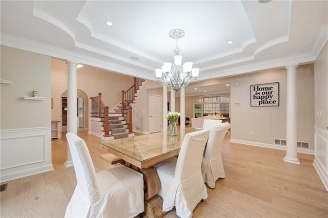 dining room with light wood-type flooring, an inviting chandelier, stairway, crown molding, and a raised ceiling