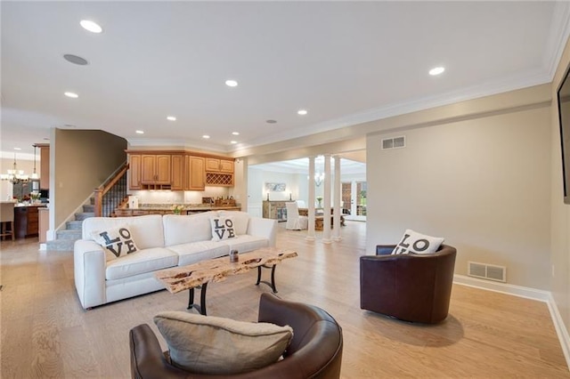 living area with crown molding, visible vents, and light wood-style floors