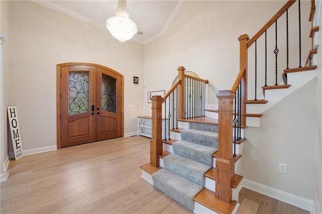 foyer entrance with arched walkways, ornamental molding, wood finished floors, stairs, and baseboards