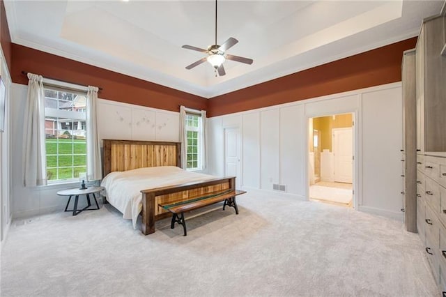 carpeted bedroom featuring ornamental molding, multiple windows, and a raised ceiling
