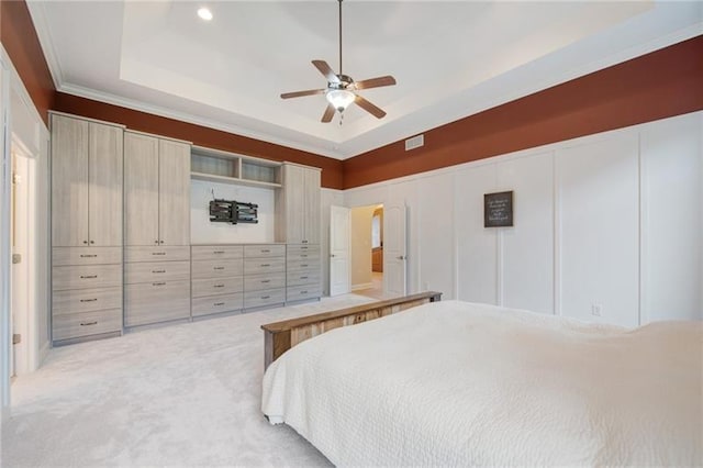 bedroom with visible vents, a decorative wall, crown molding, a tray ceiling, and light carpet
