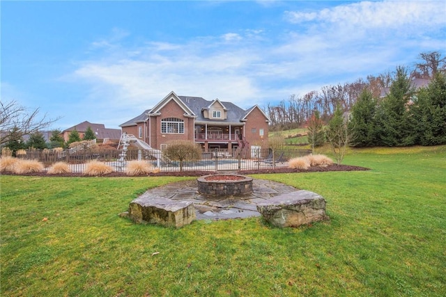 back of house featuring a lawn, a patio, fence, and an outdoor fire pit