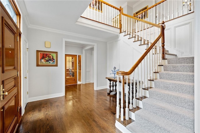 foyer entrance featuring stairway, baseboards, crown molding, and dark wood finished floors