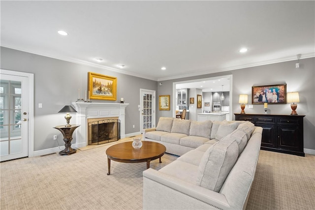 living room with a glass covered fireplace, baseboards, ornamental molding, recessed lighting, and light colored carpet
