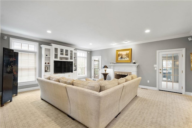 living area with baseboards, plenty of natural light, a fireplace, crown molding, and light carpet