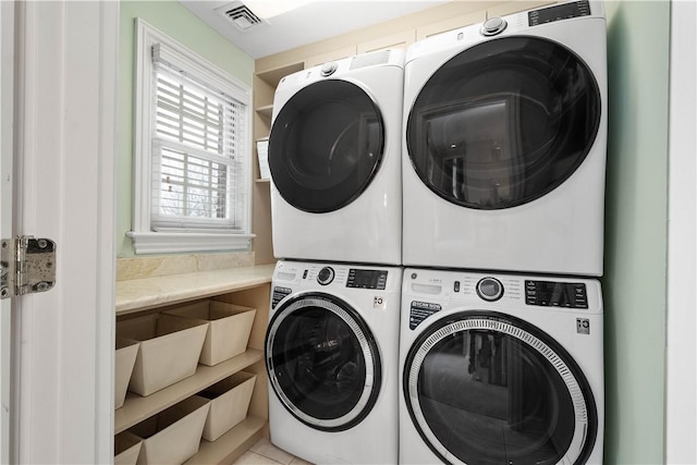 laundry area with stacked washing maching and dryer, visible vents, and laundry area