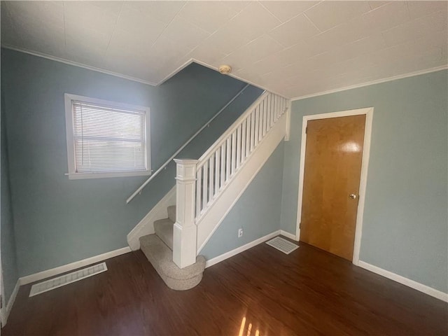 stairs featuring crown molding, visible vents, baseboards, and wood finished floors
