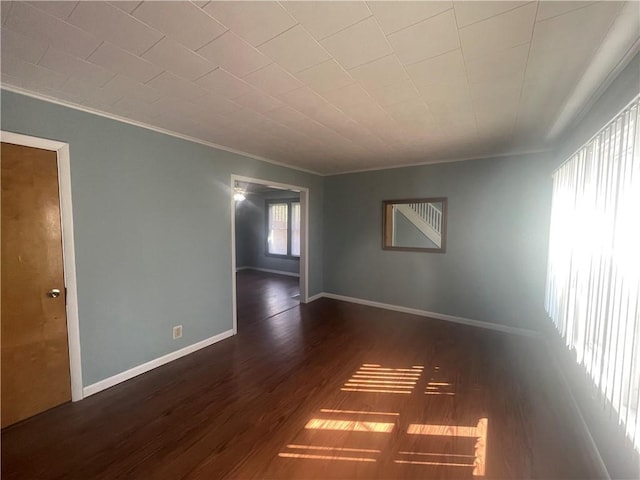 spare room with wood finished floors, baseboards, and ornamental molding