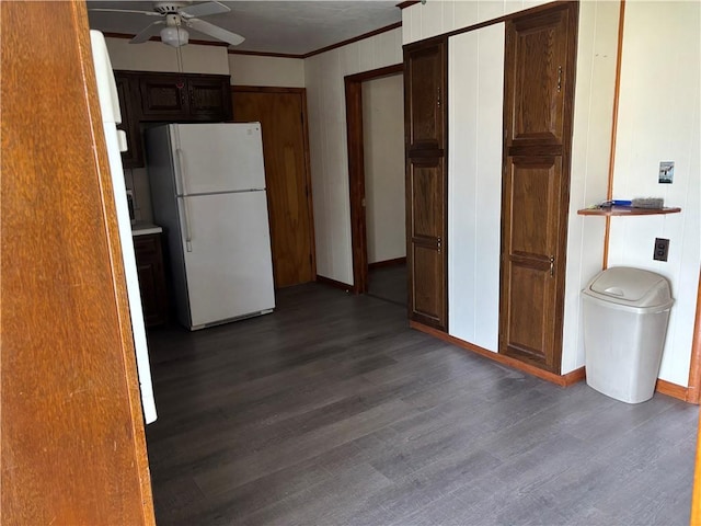 kitchen with dark wood-type flooring, ornamental molding, ceiling fan, and freestanding refrigerator