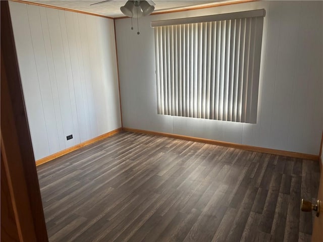 empty room with wood finished floors, baseboards, and a ceiling fan