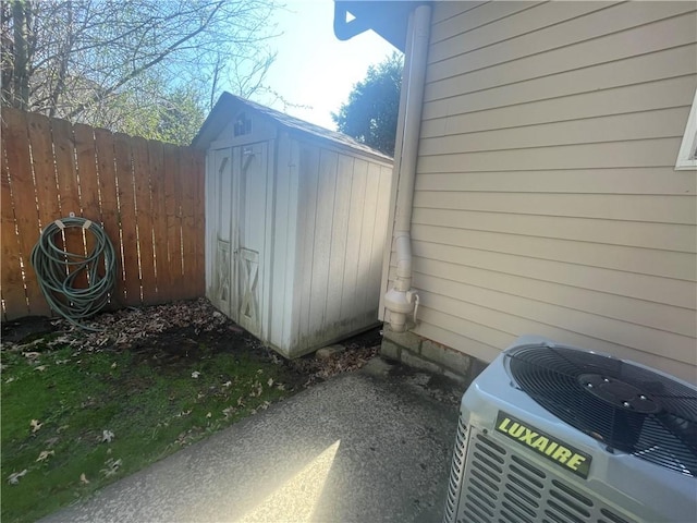 view of shed with central air condition unit and fence