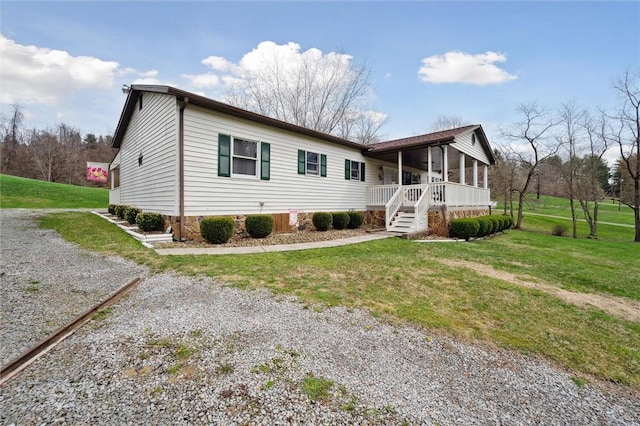 view of front of house with a front yard, a porch, and gravel driveway