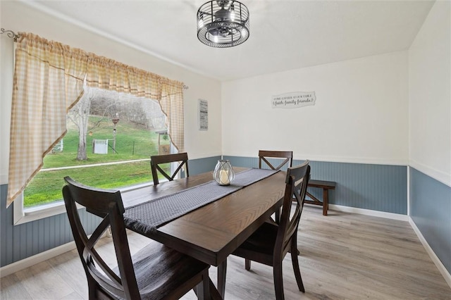 dining area featuring light wood finished floors, baseboards, and a wainscoted wall