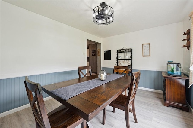 dining room featuring light wood finished floors and a wainscoted wall