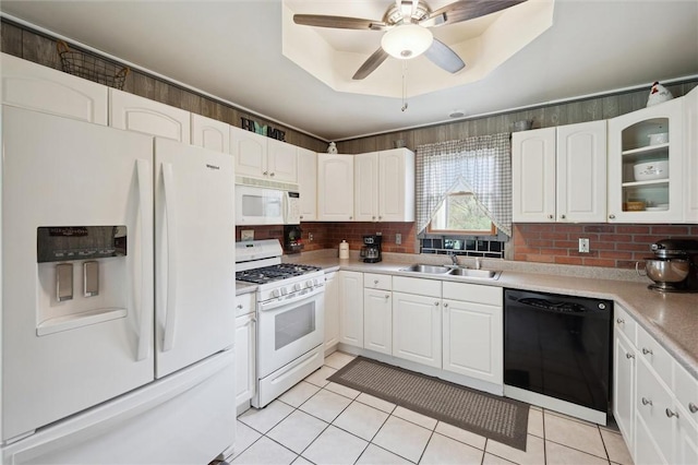 kitchen featuring glass insert cabinets, a raised ceiling, a sink, white appliances, and white cabinetry