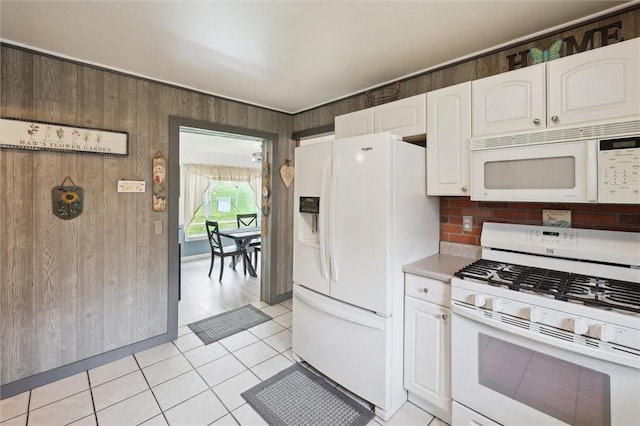 kitchen with light tile patterned floors, light countertops, white cabinetry, and white appliances