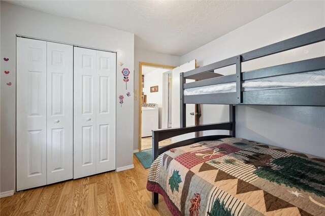 bedroom featuring a textured ceiling, a closet, wood finished floors, washer / dryer, and baseboards