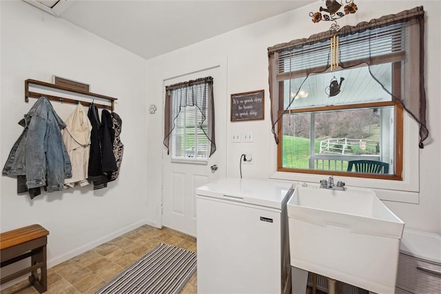 laundry room featuring baseboards, laundry area, a sink, and plenty of natural light