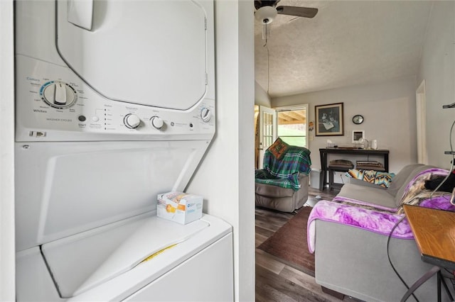 clothes washing area featuring stacked washer / dryer, laundry area, wood finished floors, and a ceiling fan