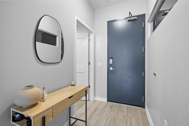 doorway to outside with light wood-style flooring and baseboards