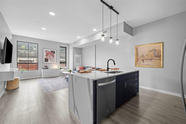 kitchen with stainless steel dishwasher, wood finished floors, a sink, open floor plan, and a center island with sink