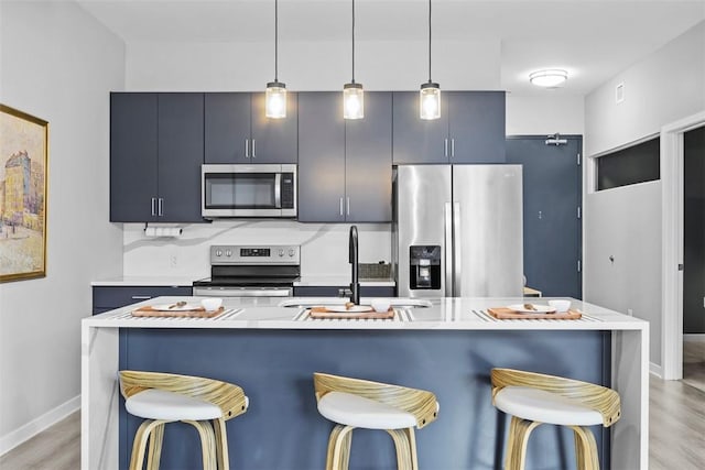 kitchen featuring a breakfast bar, light countertops, light wood-style floors, stainless steel appliances, and a sink