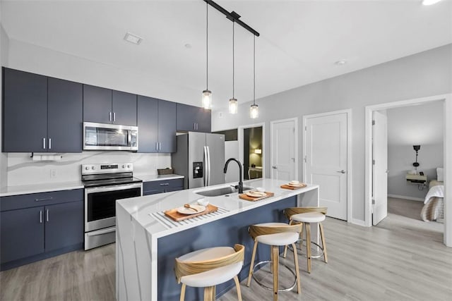 kitchen with light wood-style flooring, light countertops, a kitchen bar, appliances with stainless steel finishes, and a sink