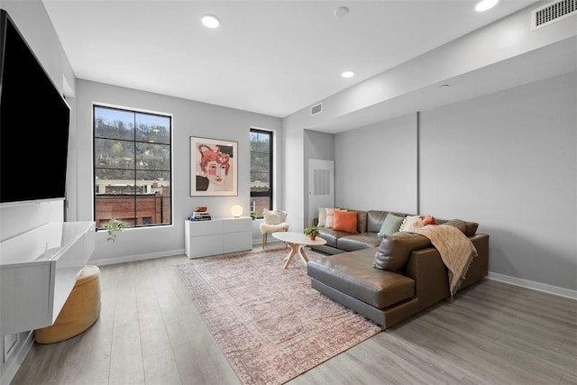 living room with recessed lighting, visible vents, baseboards, and light wood-style flooring