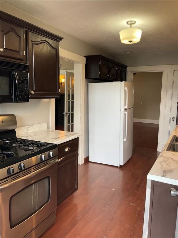 913 Russellwood Ave, Mckees Rocks, PA 15136 - kitchen with freestanding refrigerator, black microwave, gas range, dark wood-style flooring, and light countertops