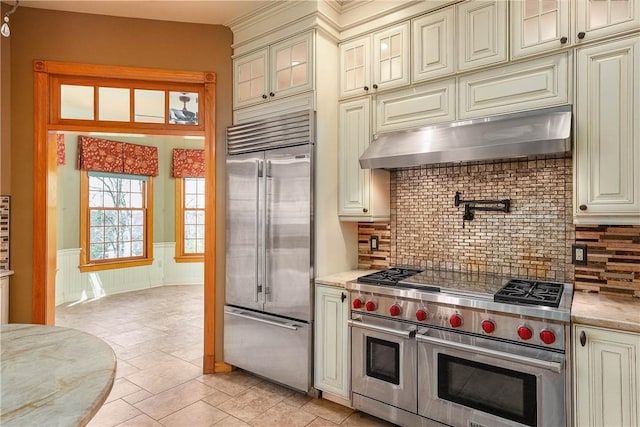 422 Heights Dr, Pine Twp Nal, PA 15044 - kitchen featuring under cabinet range hood, high end appliances, backsplash, a wainscoted wall, and cream cabinets