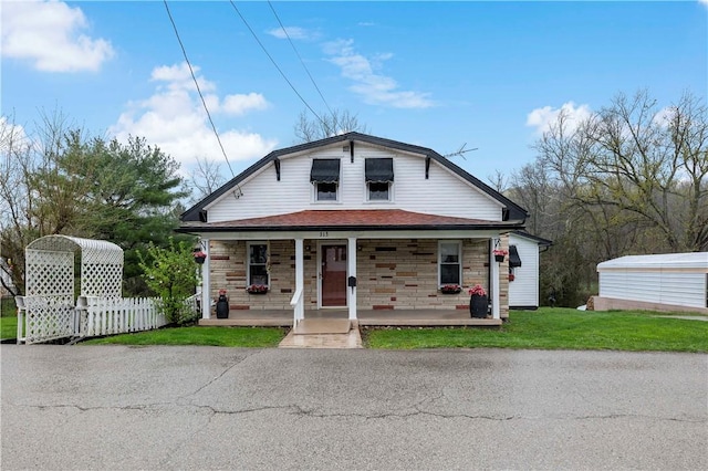 313 N Market St, Carmichaels/Cumblnd, PA 15320 - view of front of house featuring a front yard, a shingled roof, stone siding, covered porch, and fence