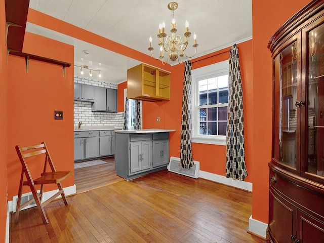kitchen featuring tasteful backsplash, hardwood / wood-style floors, gray cabinetry, and visible vents